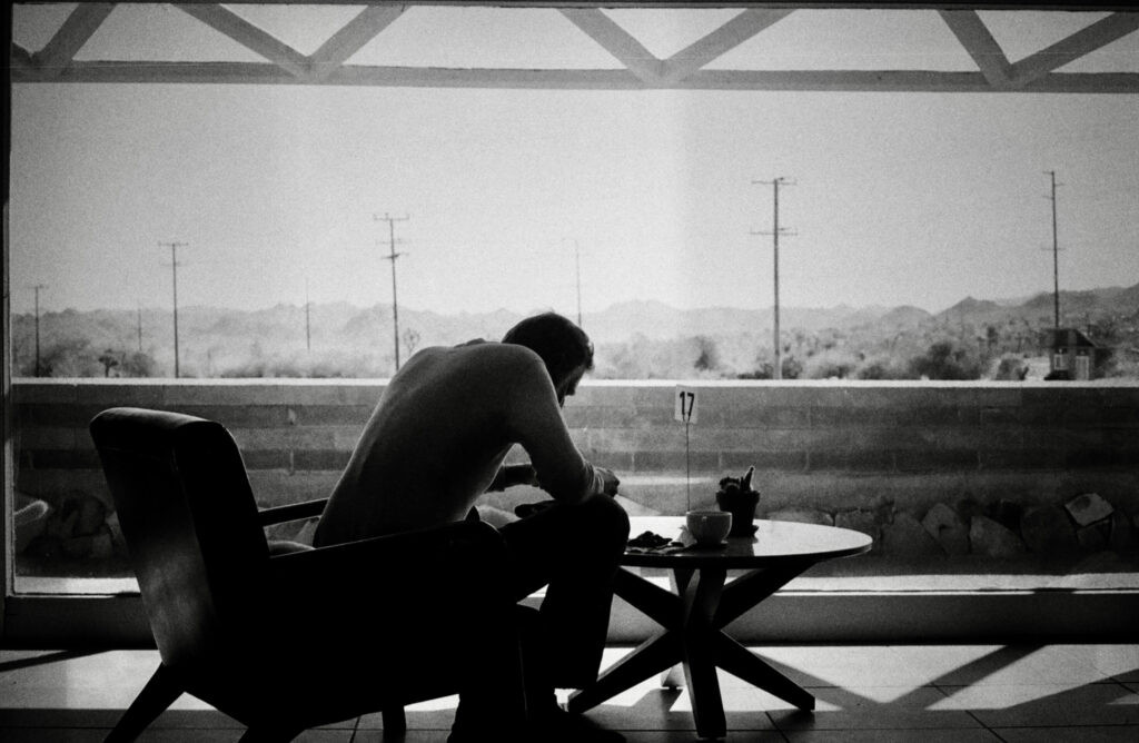 A black and white film photo of a silhouetted man eating at the Joshua Tree Retreat Center.