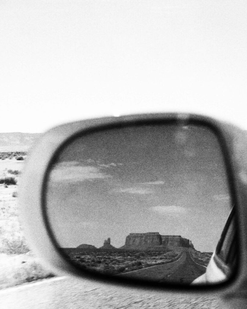 Looking back the Monument Valley as a car drives away from the park. 